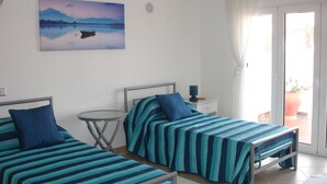 A room with two beds, a small table, and a window with curtains.