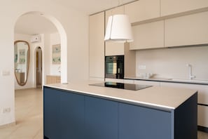 A modern kitchen with an island, a built-in oven, and a pendant light.