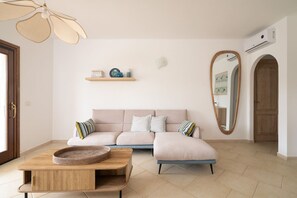 Ein Wohnzimmer mit einer Couch, einem Couchtisch, einem Spiegel und einem Deckenventilator.