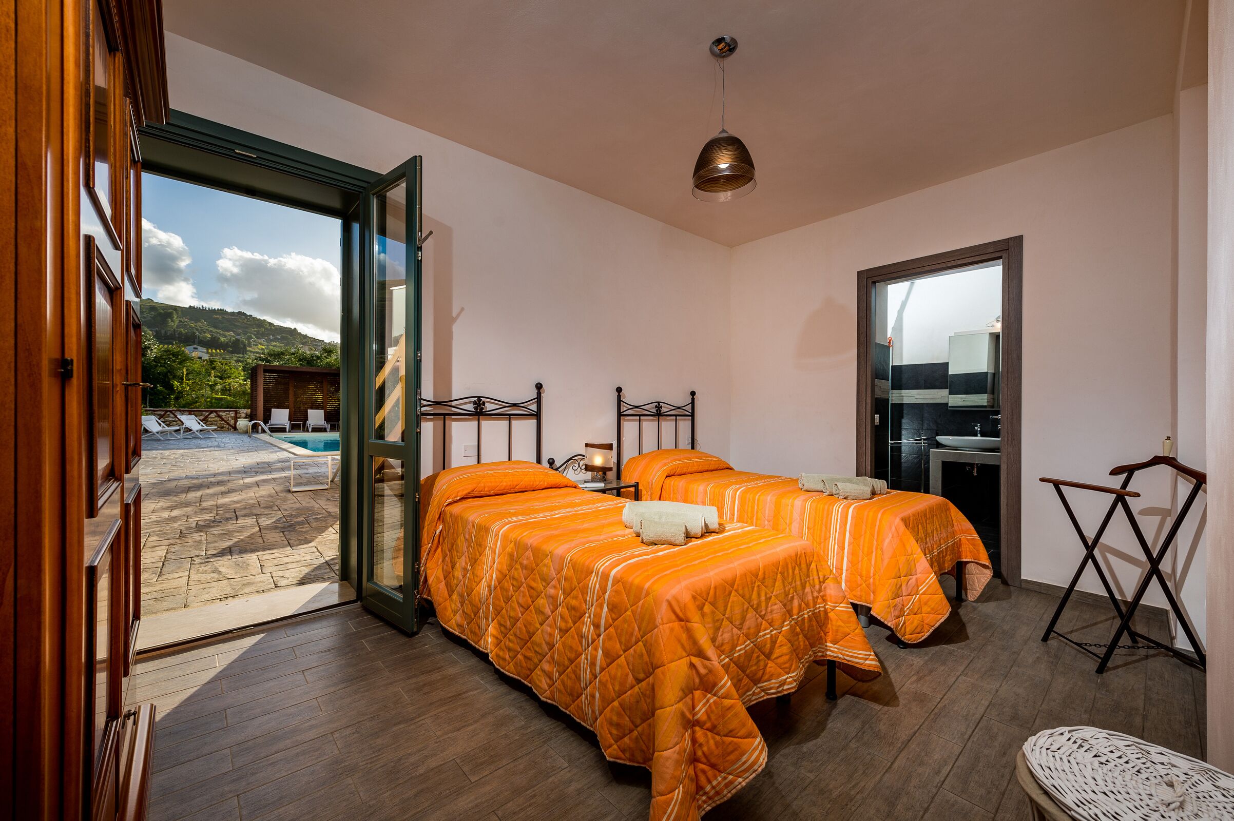 Una habitación con dos camas, un baño y vista a una piscina y montañas.
