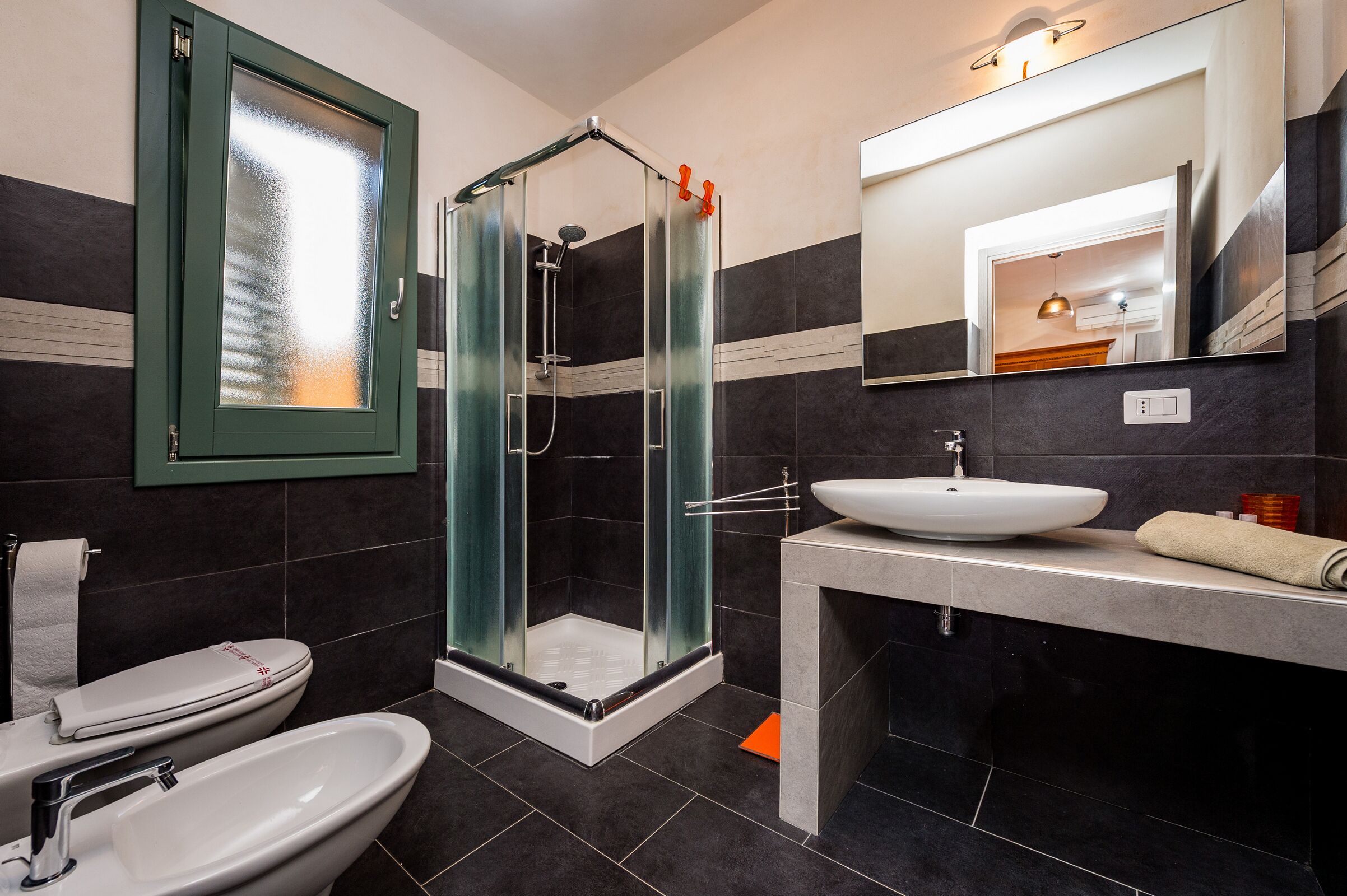 Un baño moderno con ducha envuelta en vidrio, un lavabo blanco y un espejo grande.
