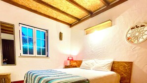 Een slaapkamer met een bed, een raam, een lamp en een decoratief wandobject.
