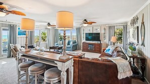 A spacious living room with a large TV, comfortable seating, and a dining area with a table and chairs. - Isle Of Palms, Luxury Oceanfront Home with Hot Tub (NORTH MYRTLE BEACH)