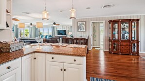 A spacious kitchen with granite countertops, white cabinetry, and pendant lighting. - Isle Of Palms, Luxury Oceanfront Home with Hot Tub (NORTH MYRTLE BEACH)