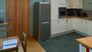 A kitchen with wooden beams, a refrigerator, an oven, and a dining area with a table and chairs. - Scottish Highlands Invergordon By NC500 Route Minimum 3 nights Any Start Day (Invergordon)