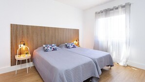 A bedroom with two beds, a wooden slat headboard, bedside lamps, and a large window with sheer curtains. - Home2Book Vibrant & Trendy Apt Santa Cruz Center (Santa Cruz de Tenerife)