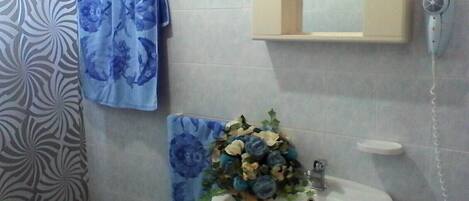 A bathroom with a white sink, a mirror, and a towel rack with a blue floral towel.