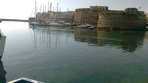 Un puerto con barcos amarrados cerca de una antigua fortificación de piedra.