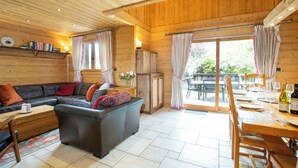 L'intérieur d'un chalet en bois, avec un canapé, une table à manger et des chaises.