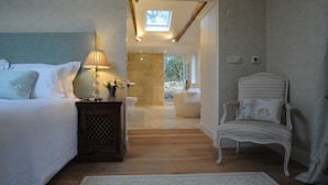 A bedroom with a bed, bedside table, lamp, chair, and a view of the bathroom. - Romantic and peaceful cottage With Far Reaching Views  (West Meon)
