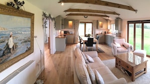 A spacious living room with a large window, a dining area, and a kitchen. - Romantic and peaceful cottage With Far Reaching Views  (West Meon)
