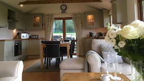 A cozy kitchen with wooden beams, a dining area with a table and chairs, and a living room with a sofa and a vase of flowers. - Romantic and peaceful cottage With Far Reaching Views  (West Meon)