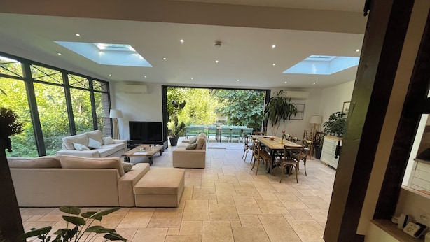 A spacious living area with a large TV, comfortable seating, a dining table, and a view of the outdoors.