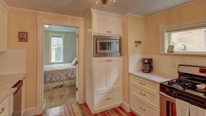 A compact kitchen with white cabinetry, a stainless steel refrigerator, a gas stove, and a window with a view.