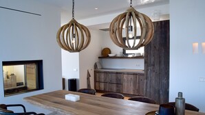 Un comedor moderno con una mesa de madera, sillas de cuero y lámparas colgantes de madera rústica.