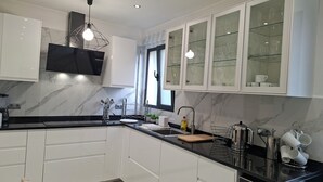 Eine moderne Küche mit weißen Schränken, einer Marmor-Spritzschutzwand und einer schwarzen Arbeitsplatte.