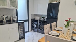 Eine moderne Küche mit integriertem Wasch- und Trockner, weißen Schränken und einem Essbereich mit Tisch für zwei Personen.