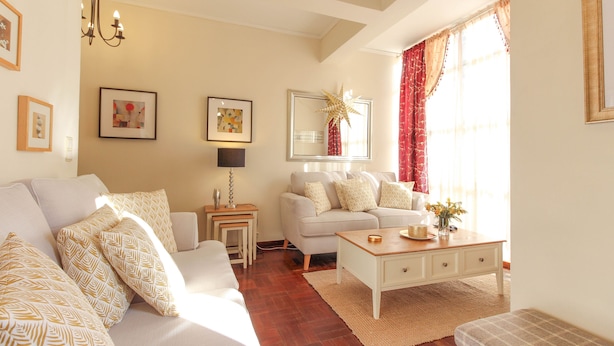 Ein Wohnzimmer mit einer Couch, einem Couchtisch und einer Lampe. An den Wänden hängen gerahmte Bilder und es gibt eine Stern-Dekoration.