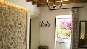 A room with a stone wall, a wooden bench, a radiator, and a window with a view of flowers. - Typical Majorcan finca with pool, wireless, garden, barbecue and heating (Santanyi)