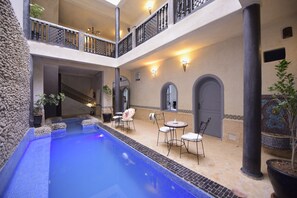 A multi-level outdoor pool area with a staircase, seating, and decorative lighting.