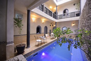A pool area with a two-story balcony, potted plants, and outdoor seating. - Private RIAD with heated pool, Jacuzzi and hotel service. 5 suites (Marrakech)