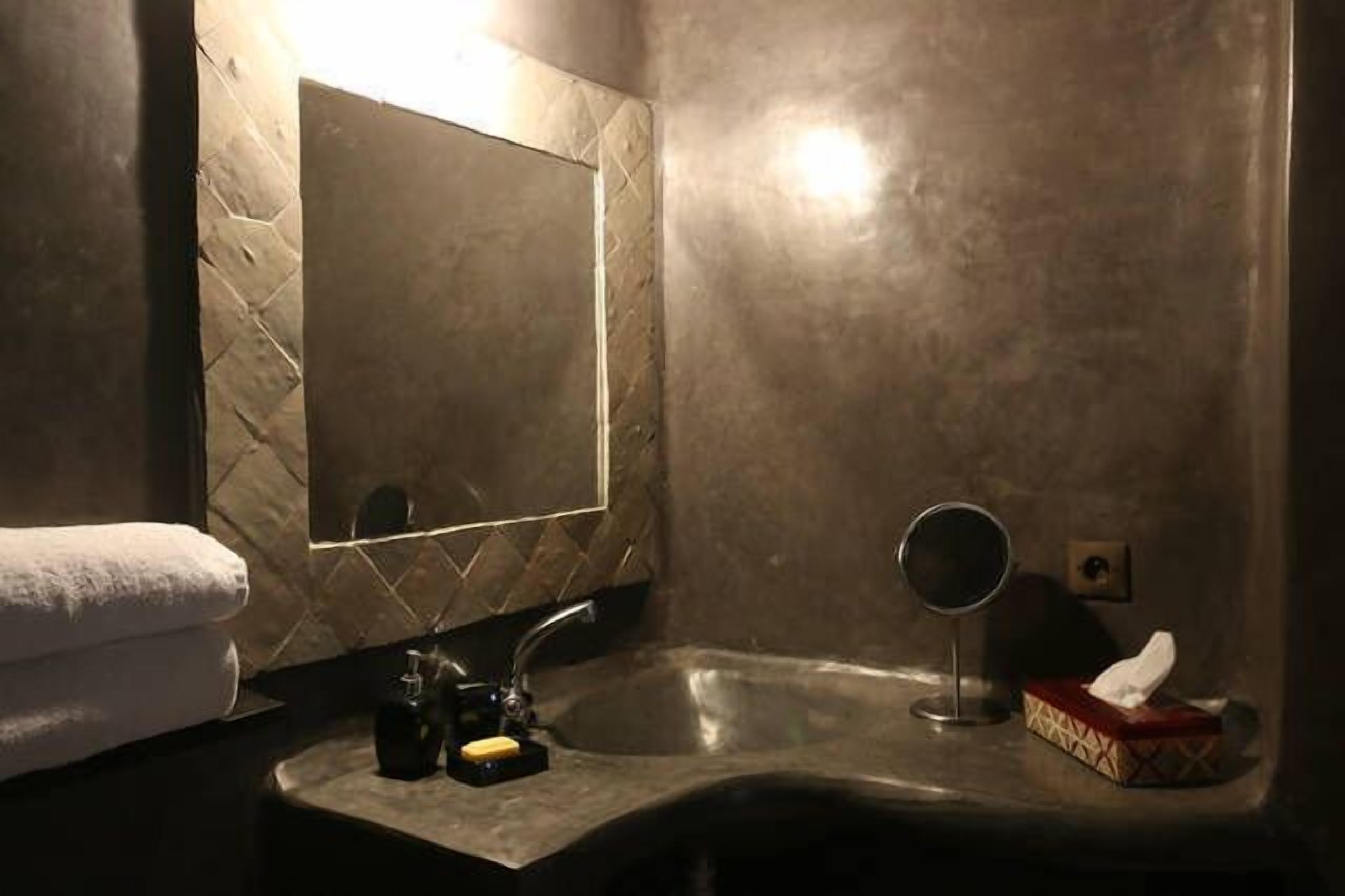 A bathroom with a mirror, sink, and towel.