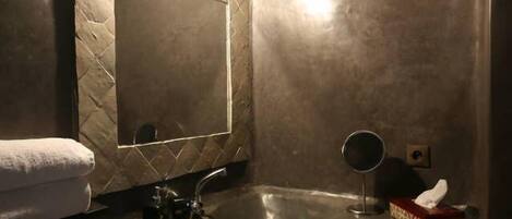 A bathroom with a mirror, sink, and towel.