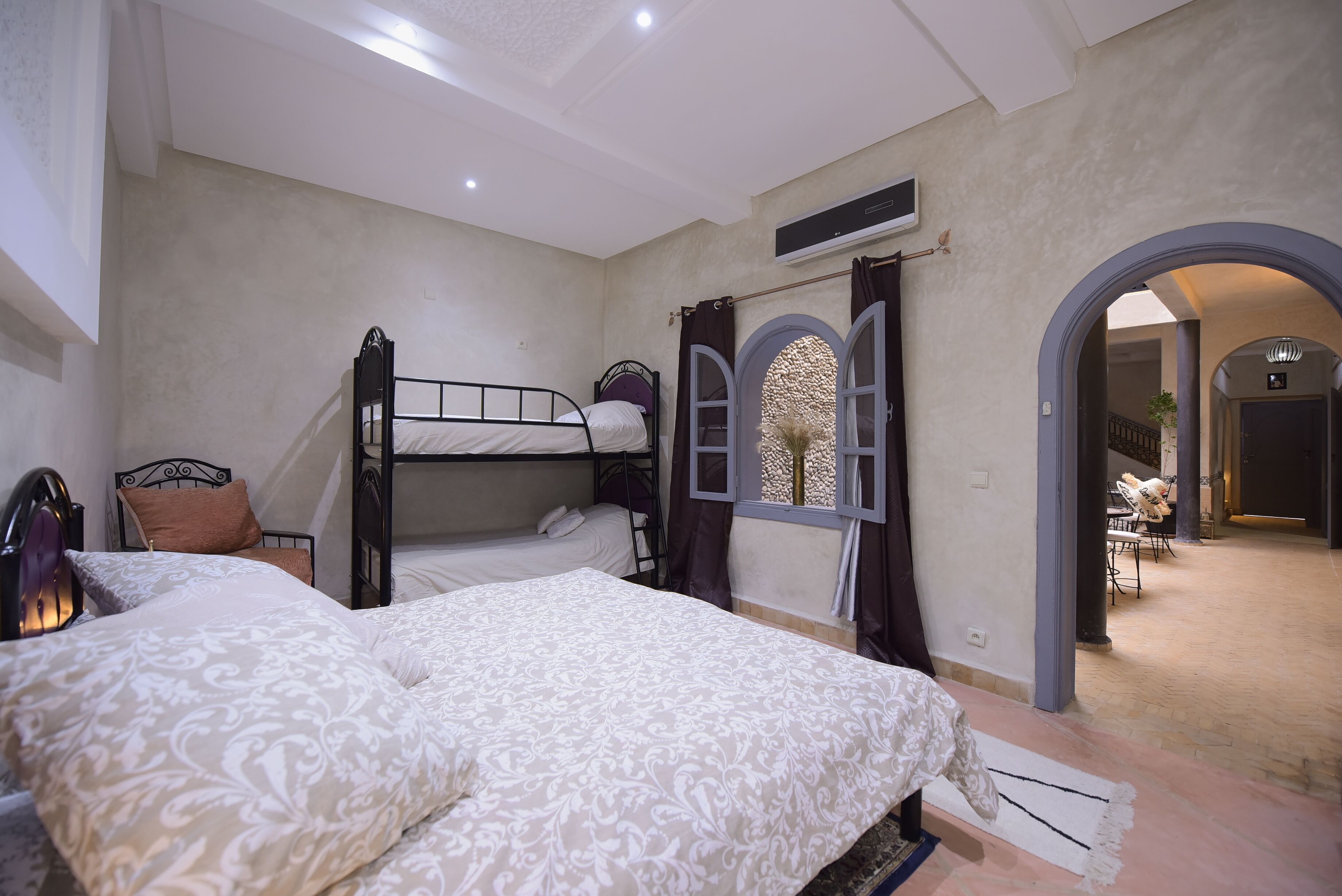 A bedroom with bunk beds, a window with curtains, and a view into a dining area.