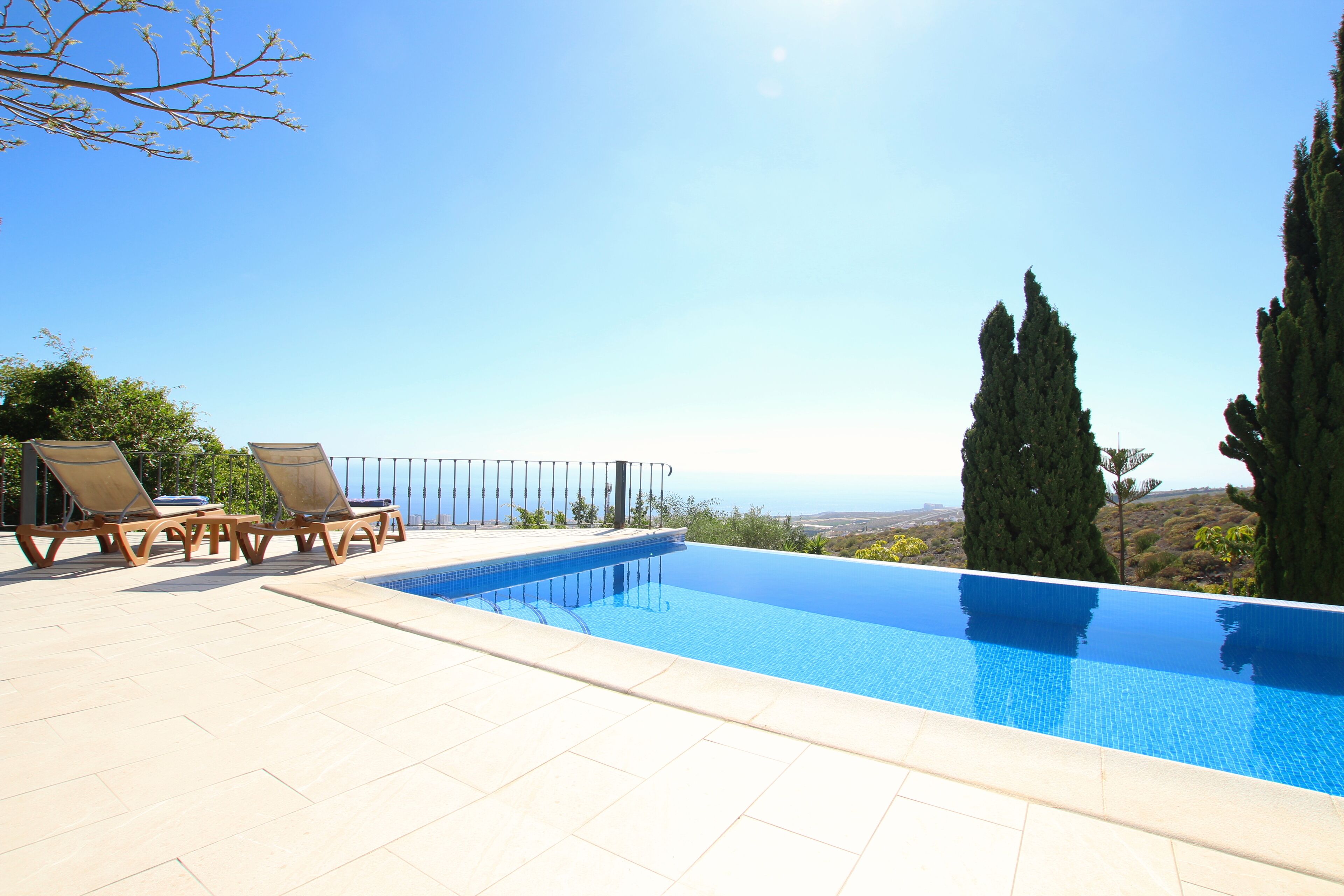 Une piscine d’eau bleue et limpide, dotée de chaises longues et offrant une vue sur le paysage.