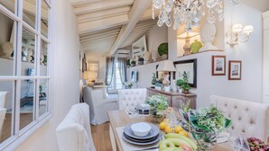 Ein geräumiger Essbereich mit hoher Decke, einer eleganten Kronleuchter und verschiedenen Tischarrangements, darunter Früchte und Blumen.