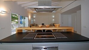 Una cocina moderna con una isla central, extractor de acero inoxidable y horno empotrado.