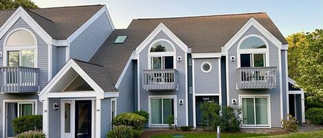 A two-story residential building with a gabled roof, dormer windows, and a front porch.