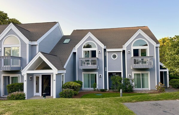 A two-story residential building with a gabled roof, dormer windows, and a front porch.