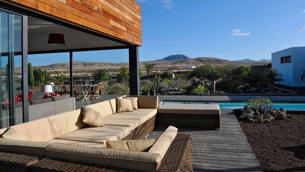 Un espace extérieur moderne, aménagé avec une terrasse en bois, un canapé confortable et une piscine.