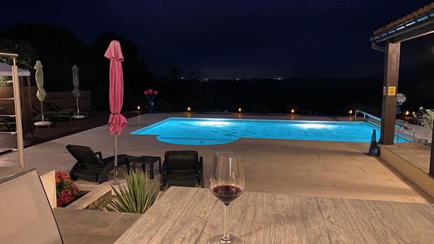Una piscina exterior amb vista al mar de nit.