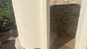 Un pati de pedra amb una xemeneia integrada i una paret amb arc de pedra.