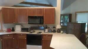 A kitchen with wooden cabinets, a microwave, a stove, and a sink. - Pet Friendly Home, Short Walk to the Beach! (1807) (Wellfleet)