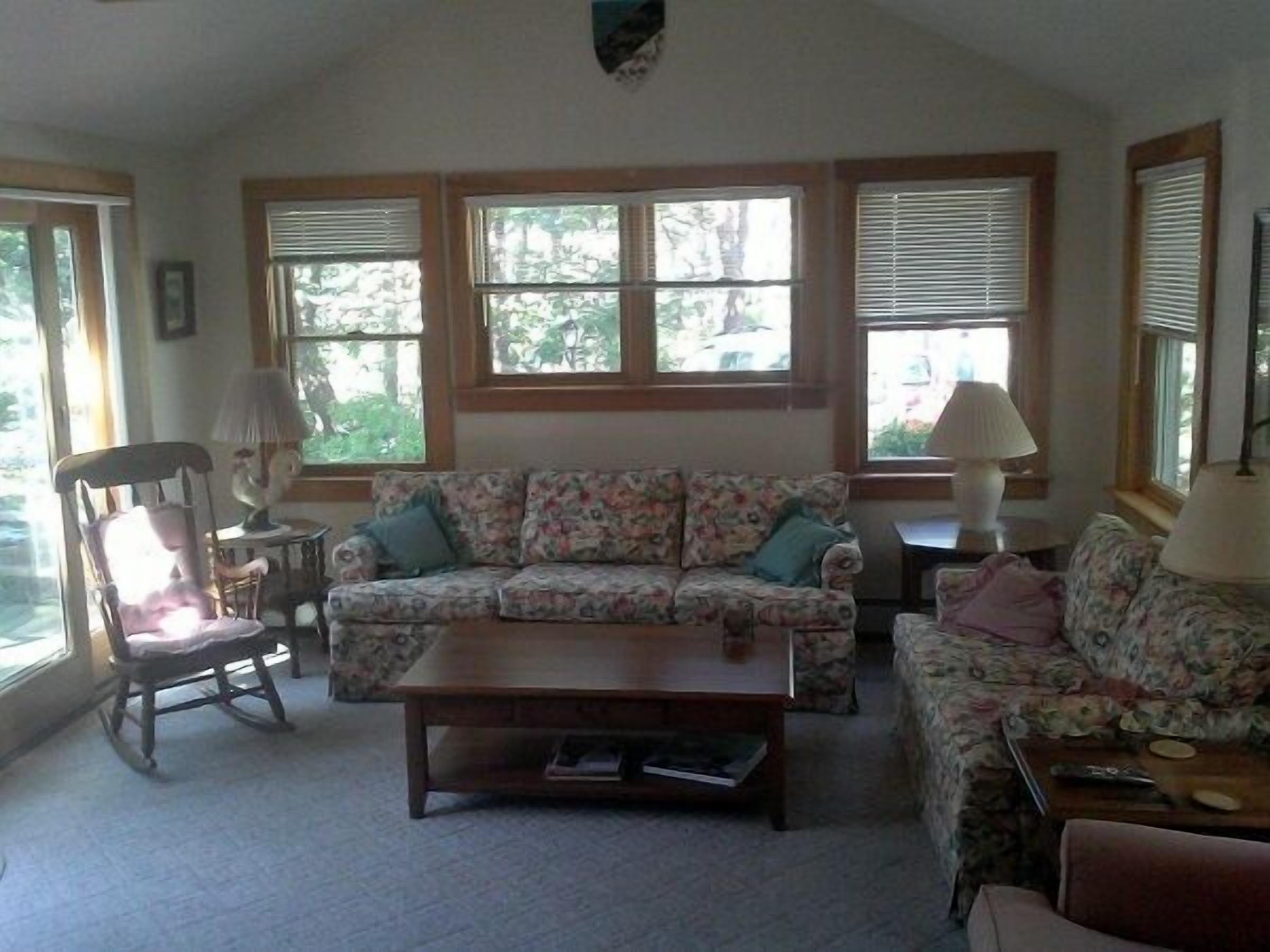 A living room with a floral sofa, a wooden coffee table, and two lamps.