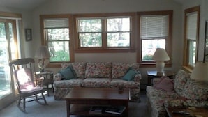 A living room with a floral sofa, a wooden coffee table, and two lamps. - Pet Friendly Home, Short Walk to the Beach! (1807) (Wellfleet)