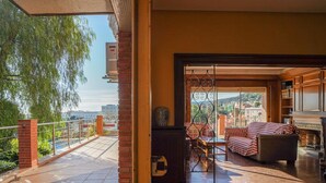 A spacious balcony with a tiled floor, a seating area with a sofa and armchairs, and a view of the cityscape. - Bed&BCN Hills House with swimming pool (Barcelona)