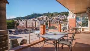 A terrace with a table and chairs, overlooking a cityscape with buildings and a hill. - Bed&BCN Hills House with swimming pool (Barcelona)