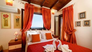 Ein Hotelzimmer mit einem großen Bett, roten Vorhängen und Kunstwerken an den Wänden.