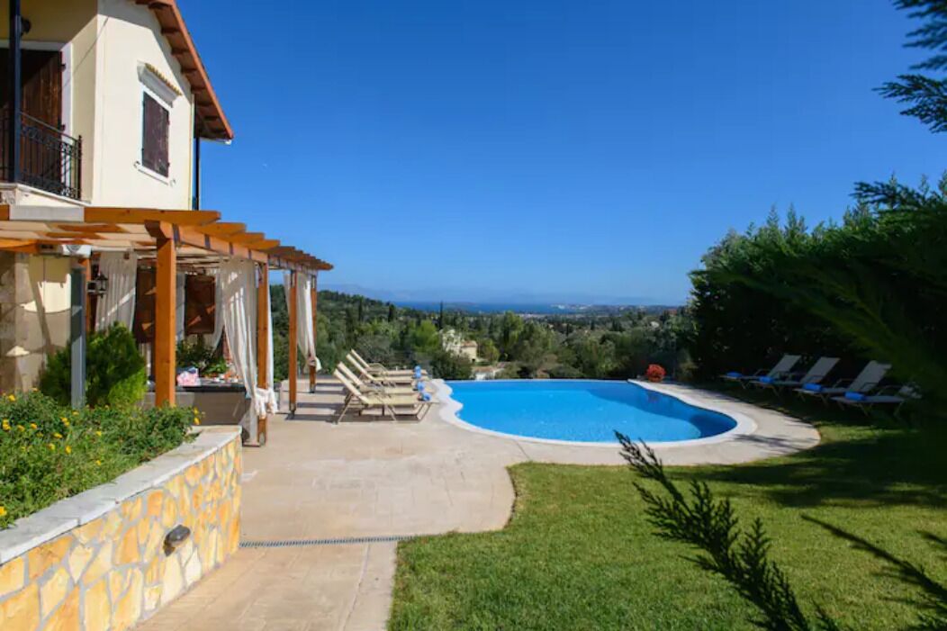 Une maison avec une piscine, un patio couvert et une vue sur la mer.