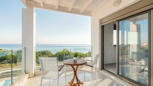 A balcony with a table and chairs, a glass door, and a view of the sea. - Sea La vie Villa in Kiotari (RHODES)