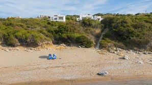 A beach with a clear view of a row of white buildings in the background. - Sea La vie Villa in Kiotari (RHODES)