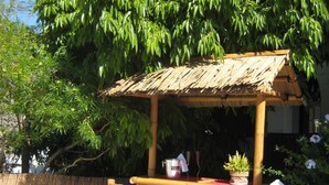 A bamboo structure with a thatched roof, a table, and chairs, surrounded by lush greenery and a clear blue sky. - La casa del molino-Ideal for Two (Mogan)