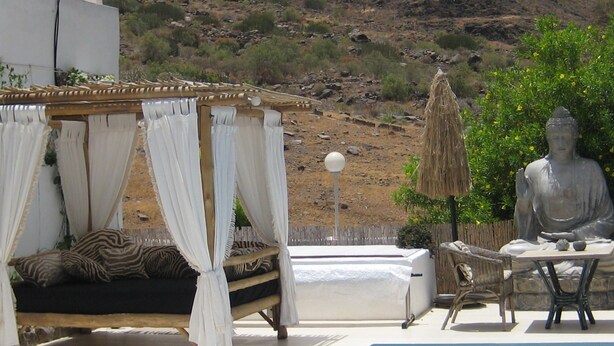 A pool area with a Buddha statue, a canopy bed, and a dining table. - La casa del molino-Ideal for Two (Mogan)