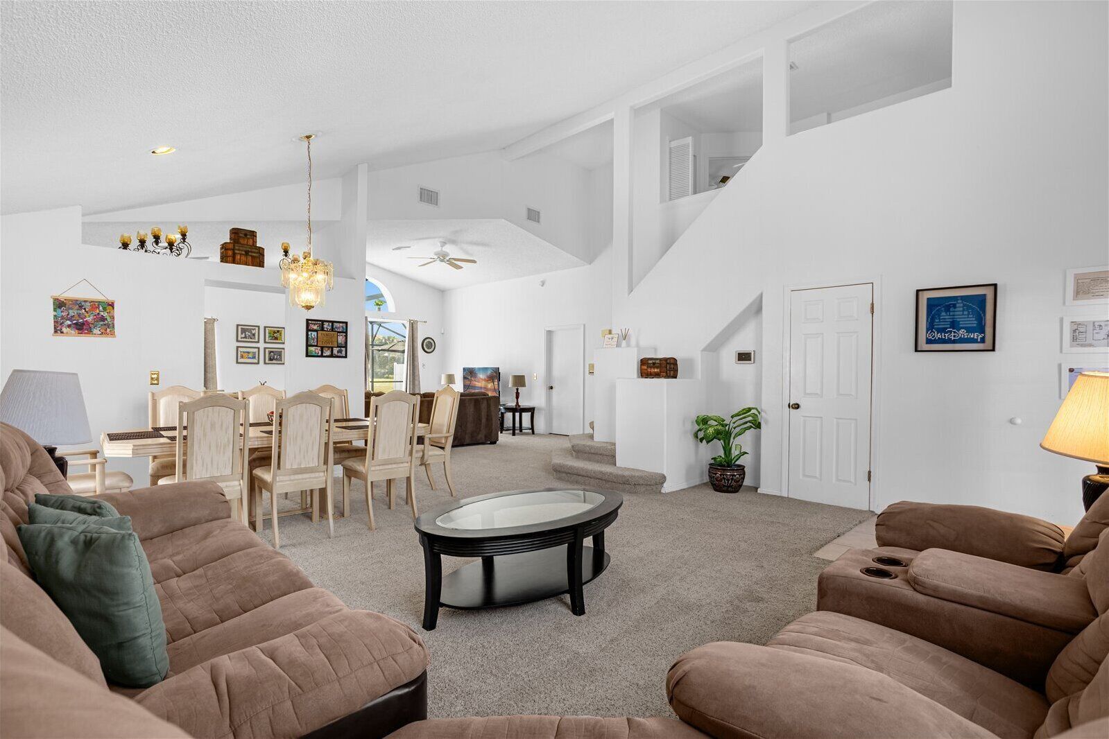 Un vaste salon doté de hauts plafonds, un coin repas et un escalier menant à l’étage supérieur.
