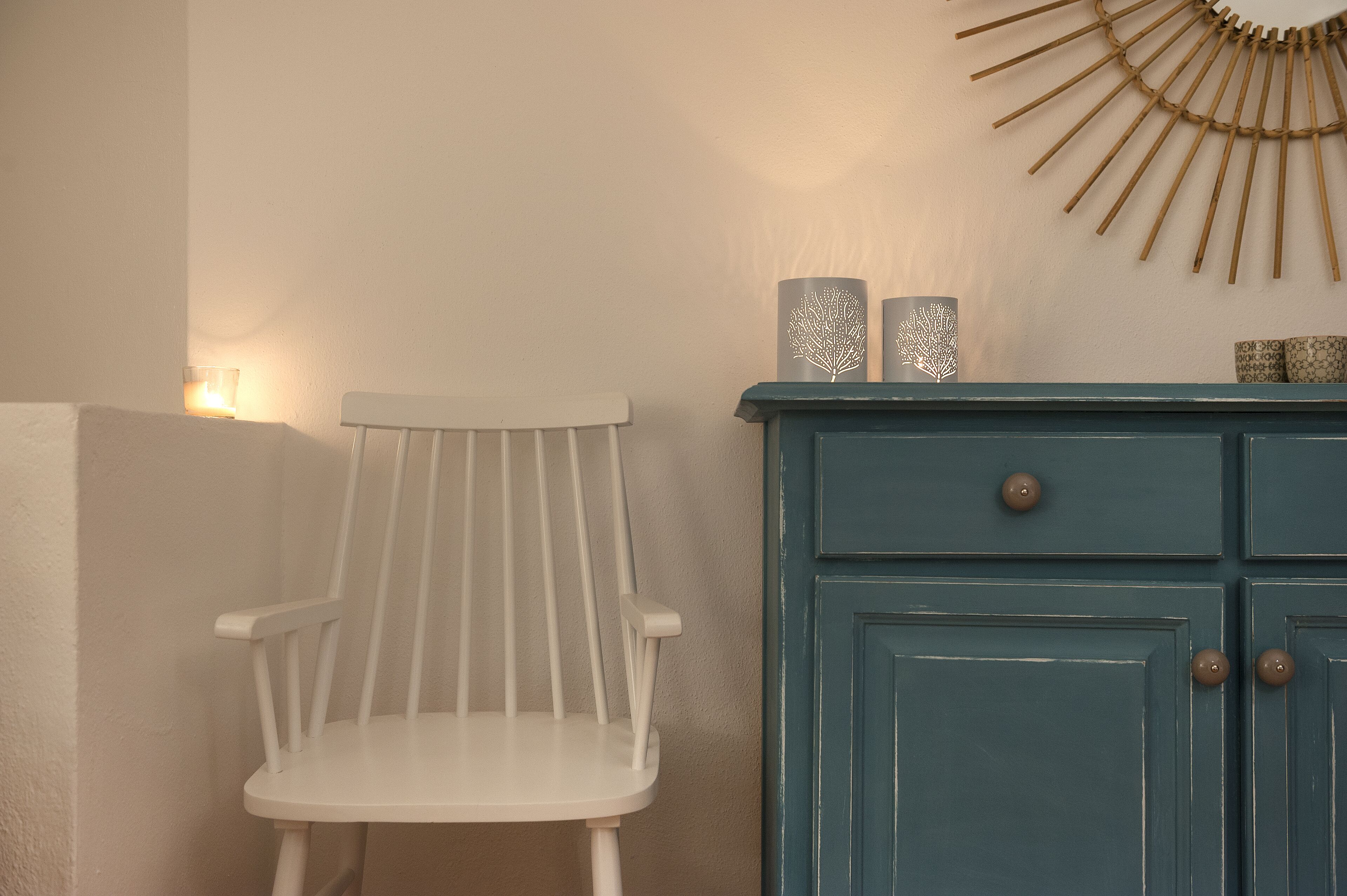 Una silla blanca, un mueble azul y un objeto decorativo en la pared.