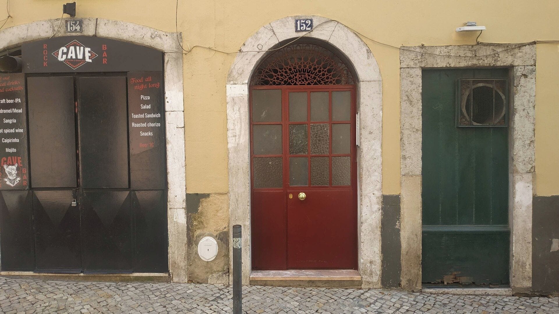 A building with a red door, a black door with a sign, and a green door.